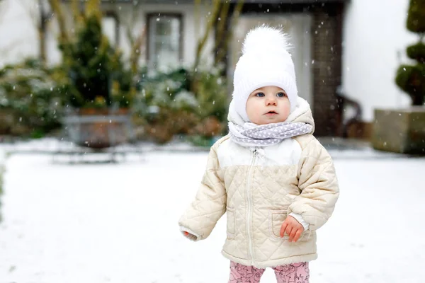 Adorable petite fille qui fait ses premiers pas à l'extérieur en hiver. Bébé mignon apprenant à marcher. Enfant qui s'amuse par temps froid. Porter des vêtements chauds bébé rose et chapeau avec des bobbles. — Photo