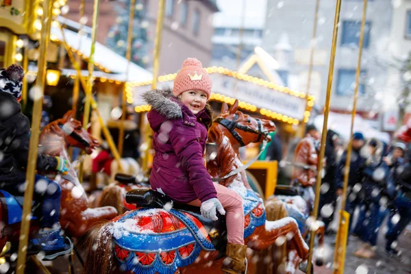 Schattig kind meisje rijden op een merry go ronde carrousel paard op kerst kermis of markt, buiten. Gelukkig kind plezier op traditionele familie xmas markt in Dresden, Duitsland — Stockfoto