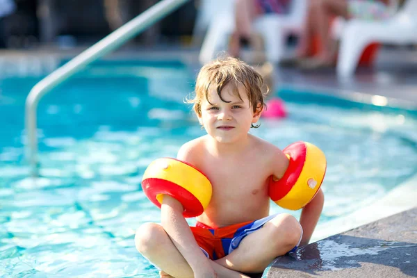 Gelukkig kind jongetje met plezier in een zwembad. Actieve gelukkig kind leren om te zwemmen. met veilige floaties of swimmies. Familie, vakanties, zomer concept — Stockfoto