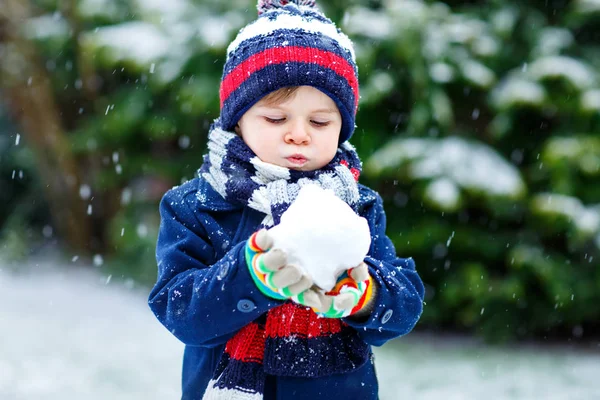 Cute little funny child in colorful winter fashion clothes having fun and playing with snow, outdoors during snowfall. Active outdoors leisure with children. Kid boy and toddler catching snowflakes. — Stock Photo, Image