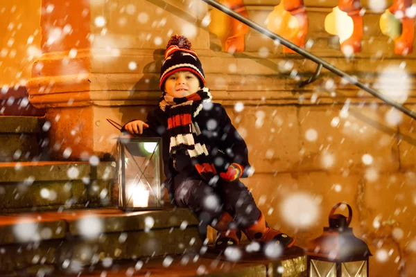 一个可爱的小男孩，带着灯笼在教堂附近的楼梯上。在德国的圣诞市场上快乐的孩子。孩子们在寒冷的冬日伺候父母 — 图库照片