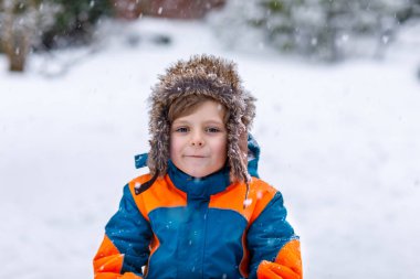 Mutlu çocuk kışın karla eğleniyor.