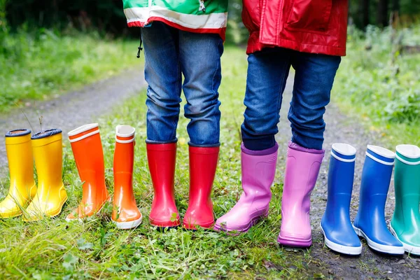 Kleine kinderen, jongens en meisjes in kleurrijke regen laarzen. Kinderen die permanent in de herfst bos. Close-up van schoolkinderen en verschillende rubber laarzen. Schoenen en mode voor regenachtige val — Stockfoto