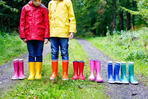 작은 아이, 남자와 여자 다채로운 장화에 가 숲에 서 있는 아이 들. Schoolkids 및 다른 고무 부츠의 클로즈업입니다. 신발 및 비가을 위한 패션 — 스톡 사진