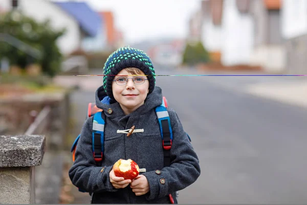 Little kid boy with eye glasses walking from the school and eating apple — Stock Photo, Image