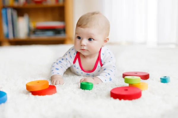 Söt baby flicka som leker med färgglada trä skallra leksak — Stockfoto
