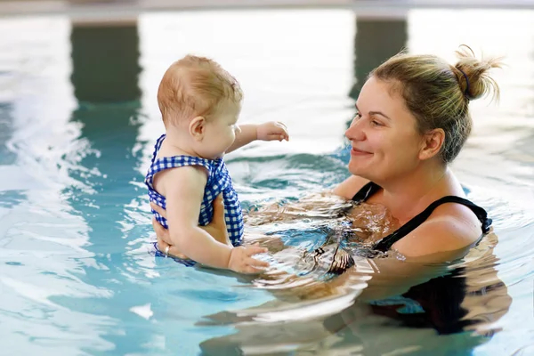 Happy mother swimming with cute adorable baby girl daughter in swimming pool spending spa vacations — Stock Photo, Image