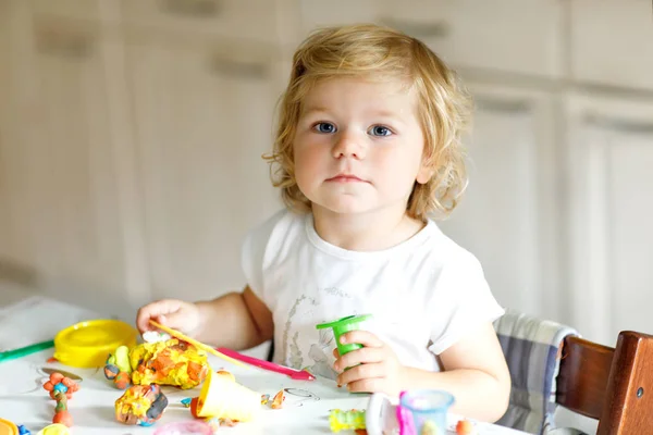Renkli killi, sevimli, küçük bir kız. Sağlıklı bebek oyun oynuyor ve oyun hamurundan oyuncaklar yapıyor. Küçük çocuk kil kalıp ve öğrenim — Stok fotoğraf