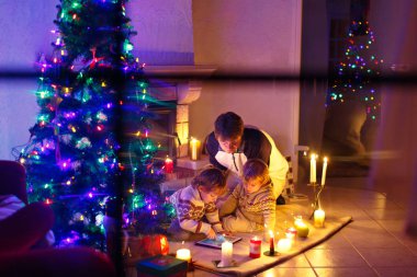 Baba ve Noel arifesi zamanında şömine baca tarafından oturan iki küçük çocuğu.