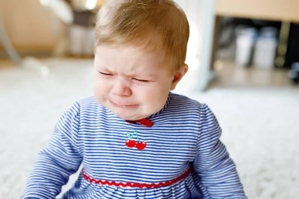 Милая маленькая грустная девочка плачет. Голодный или уставший ребенок сидит в помещении и плачет — стоковое фото