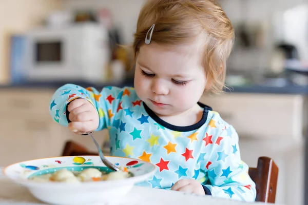 Menina adorável comendo de sopa de macarrão vegetal colher. conceito de comida, criança, alimentação e pessoas — Fotografia de Stock