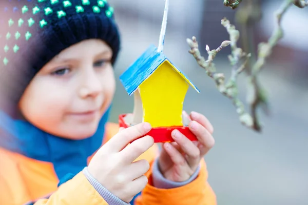 冬の給餌のための木の鳥の家をぶら下げ小さな子供 — ストック写真