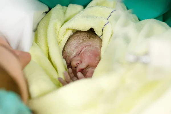 Bebê recém-nascido envolto em cobertores após o nascimento. Mãe procurando pela primeira vez na filha recém-nascida — Fotografia de Stock
