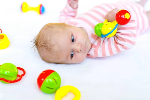 Niedliche Baby-Mädchen spielen mit bunten Rasselspielzeug — Stockfoto