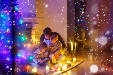 Baba ve Noel arifesi zamanında şömine baca tarafından oturan iki küçük çocuğu.
