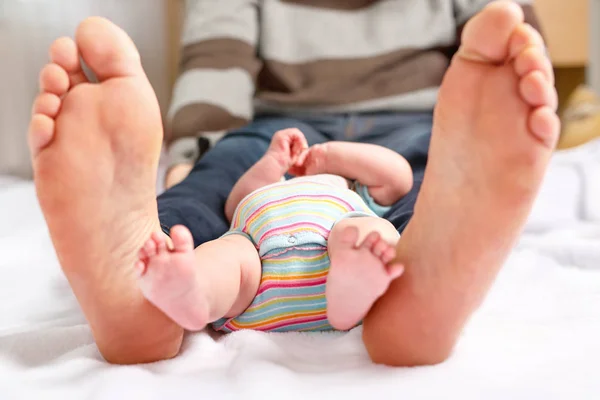 Close-up van enorme voeten van vader en kleine pasgeboren baby — Stockfoto