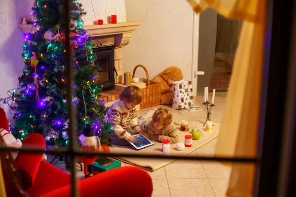 Duas crianças sentadas em uma lareira em casa no Natal — Fotografia de Stock