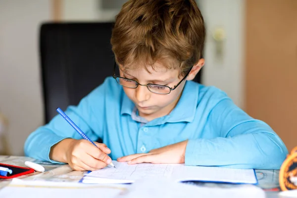 Gözlüklü, ev ödevi yapan, mektup yazan ve renkli kalemlerle matematik yapan sevimli bir çocuk. Küçük çocuk içeride egzersiz yapıyor. İlköğretim ve eğitim, hayal edin. — Stok fotoğraf