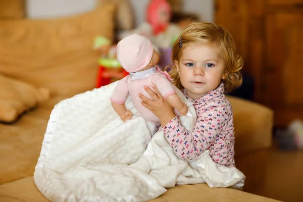 Gadis balita kecil yang manis bermain dengan boneka. Bayi yang sehat bersenang-senang dengan permainan peran, bermain sebagai ibu di rumah atau pembibitan. Putri aktif dengan mainan. — Stok Foto