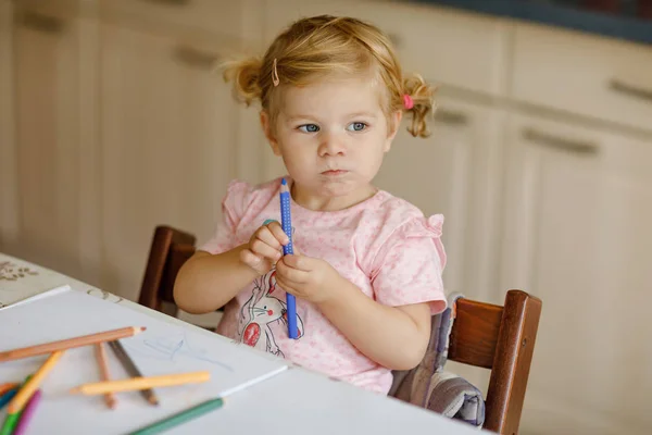 Милая очаровательная девочка учится рисовать карандашами. Маленький ребенок рисует дома, используя цветные ручки для наконечников войлока. Здоровая счастливая дочь экспериментирует с цветами дома или в детской. — стоковое фото