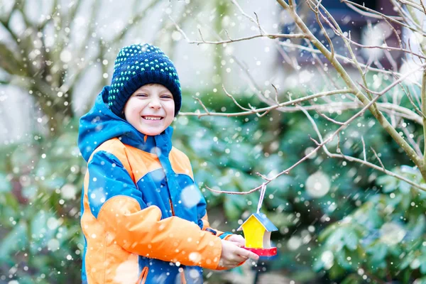 Petit garçon accroché maison d'oiseau sur l'arbre pour se nourrir en hiver — Photo