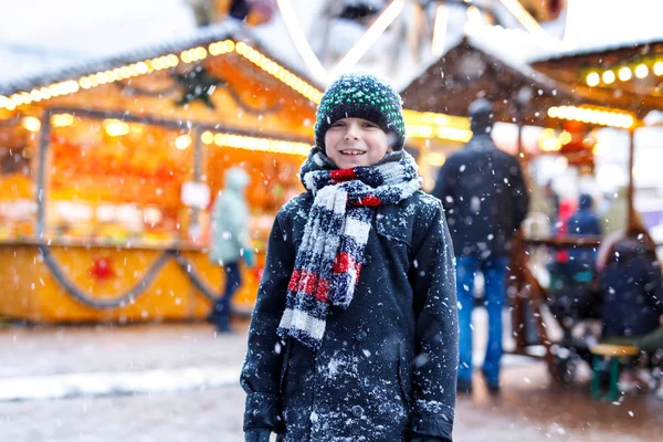 Little cute kid boy having fun on traditional German Christmas market during strong snowfall. — Stock Photo, Image