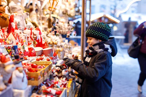 小さなかわいい子供男の子クリスマス マーケットの装飾を選択します。美しい子供のおもちゃや装飾的な装飾品のための買い物 — ストック写真
