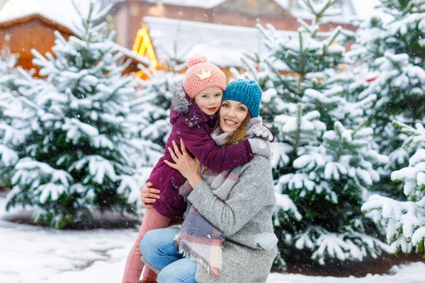 Cute little smiling kid girl and mother on christmas tree market. — Stock Photo, Image