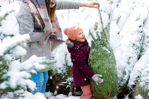 Söt liten leende kid flicka och mor på julgran marknaden. — Stockfoto