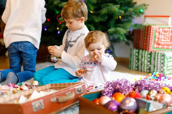 两个小男孩和可爱的女婴装饰圣诞树与老式的玩具和球. — 图库照片