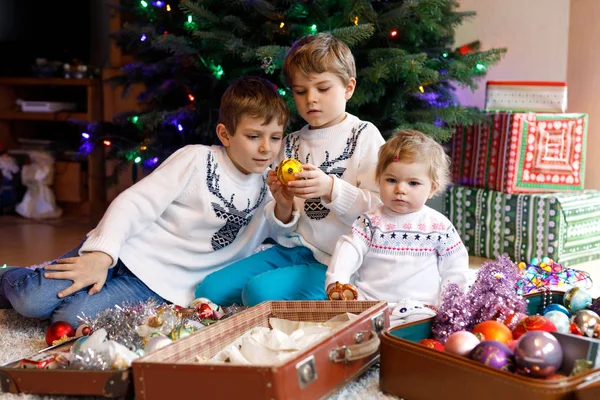 Two little kid boys and adorable baby girl decorating Christmas tree with old vintage toys and balls. — Stock Photo, Image