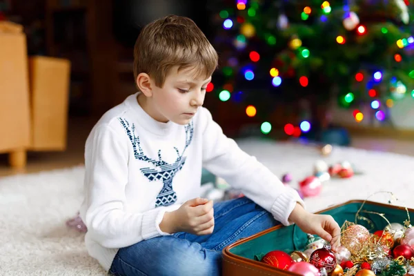 Beautiful kid boy and colorful vintage xmas toys and balls. Child decorating Christmas tree — Stock Photo, Image
