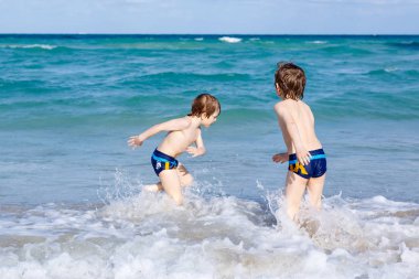 Okyanus plaj üzerinde çalışan iki çocuk çocuklar. Küçük çocuklar eğleniyor