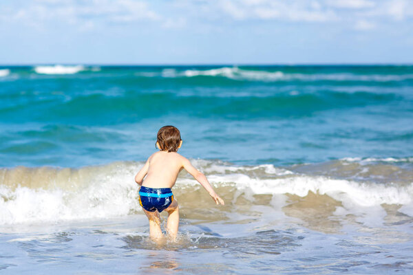 маленький блондин мальчик весело проводит время на пляже океана во Флориде
