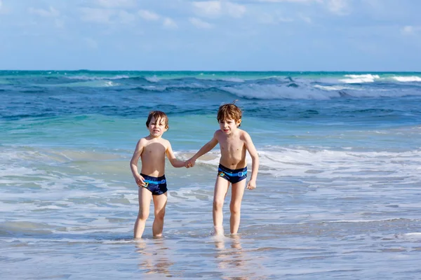 Okyanus plaj üzerinde çalışan iki çocuk çocuklar. Küçük çocuklar eğleniyor — Stok fotoğraf