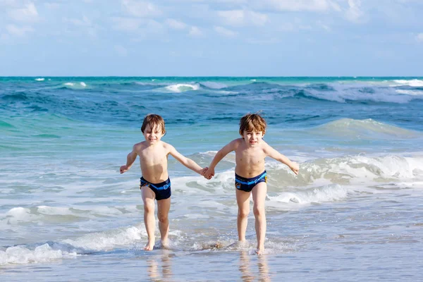 Двоє хлопчиків біжать на океанському пляжі. Маленькі діти розважаються — стокове фото