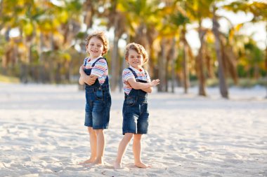 İki küçük çocuk tropik sahilde eğleniyor.