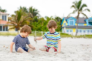İki küçük çocuk tropik sahilde eğleniyor.