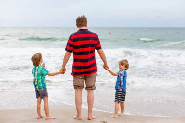 İki küçük çocuk çocuklar ve babası okyanus plaj