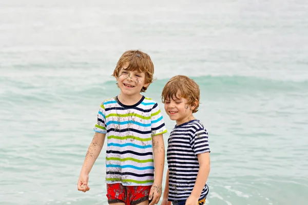 Dwie szczęśliwe małe dzieci chłopców uruchomiona na plaży oceanu — Zdjęcie stockowe