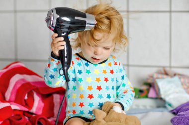 Sevimli küçük yürümeye başlayan çocuk kız yapma kıllar ile saç kurutma makinesi. Sağlıklı bebek çocuk alarak banyo sonra ıslak tüyleri ile. Güzel kız oyuncak ile eğleniyor