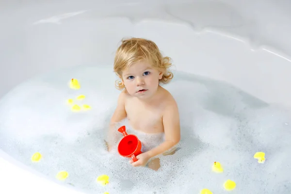 Roztomilé roztomilé malé batole dívka s koupel ve vaně. Šťastné zdravé dítě dítě hraje s hračkami gum guma a baví. Praní, čištění, hygiena pro děti. — Stock fotografie