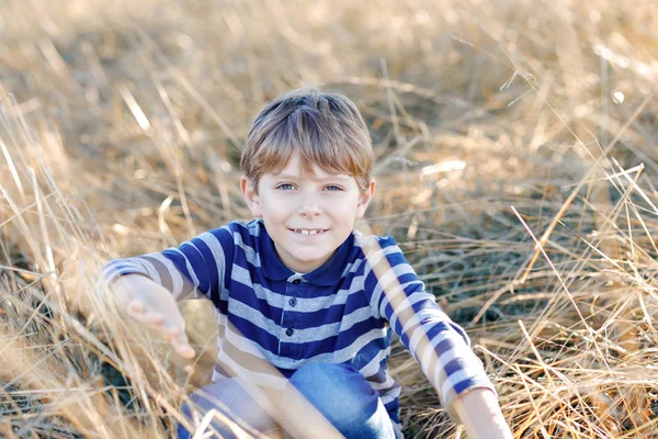 Portrait de petit garçon cool dans l'herbe sèche haute. Heureux enfant en bonne santé s'amuser par une chaude journée ensoleillée au début de l'automne. Famille, nature, amour et loisirs actifs . — Photo