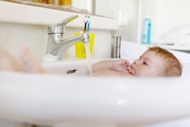 Alarak şirin bebek yıkama lavabo banyo ve musluk suyu yakala.