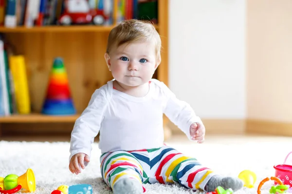 Bebek odasında eğitici oyuncaklarla oynayan sevimli bir kız. Mutlu sağlıklı çocuk evde renkli farklı oyuncaklarla eğleniyor. Bebek gelişimi ve ilk adımlar, çalmayı ve yakalamayı öğrenmek.. — Stok fotoğraf