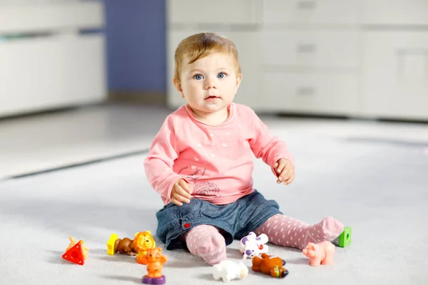 Adorável menina brincando com brinquedos domésticos animais como vaca, cavalo, ovelhas, cão e animais selvagens como girafa, elefante e macaco. Criança saudável feliz se divertindo com brinquedos diferentes coloridos em casa — Fotografia de Stock