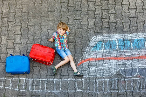 Malý kluk kluk baví s obrázkem spěšný vlak kreslení na asfalt s barevné křídy — Stock fotografie