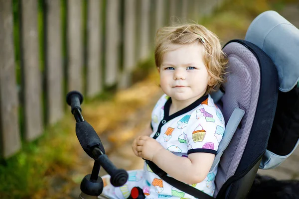 Schattig schattig peuter meisje zittend op duwen bicyle of driewieler. Klein kindje gaat wandelen met ouders op zonnige dag. — Stockfoto