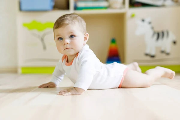 Niedliche Baby-Mädchen lernen Krabbeln und Sitzen im Kinderzimmer — Stockfoto