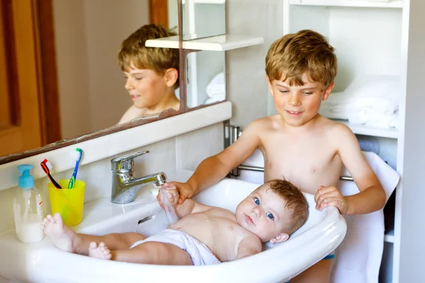 Schattige schattig baby nemen bad in wassen gootsteen en waterkraan pak. — Stockfoto